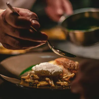 A chef meticulously garnishes a dish for a private dining experience.