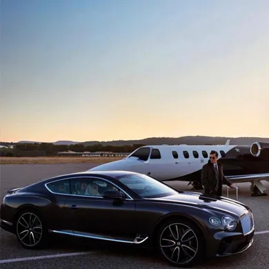 A businessman stands next to a private jet and a luxury car, a perfect image for VIP transfers.