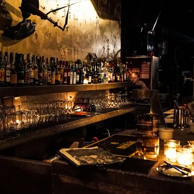 A rustic bar with shelves filled with bottles of whiskey and other spirits. Ambiance for a whiskey and cigar tasting event.